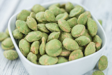 Portion of Wasabi coated Peanuts on wooden background (selective focus)