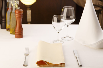 Fork and table knife with napkin arranged in elegant setting, Wineglass in the background, Selective focus with soft light