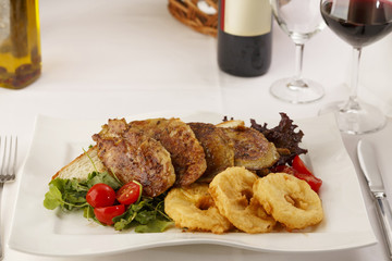 Chicken with breaded pineapple arranged on a plate, Wine bottle and wineglass in background, Traditional dish in elegant setting, Selective focus with soft light