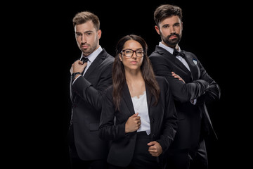 confident businesspeople posing in black formal wear, isolated on black