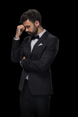 handsome bearded upset businessman in bow tie and black suit, isolated on black