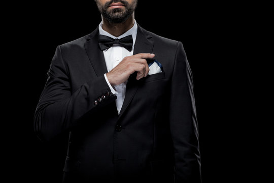 cropped view of businessman in bow tie and tuxedo with napkin, isolated on black