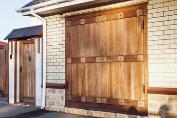 Beautiful modern wooden gate against a white brick wall.