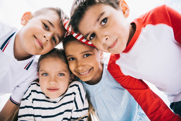 Close-up portrait of happy multiethnic kids standing together and smiling at camera