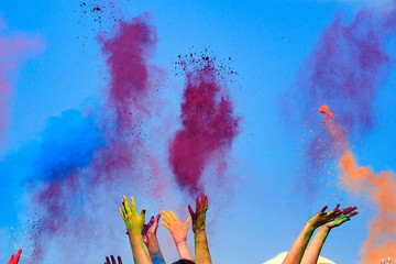 At the color Holi Festival, hands in the air, blue sky behind
