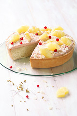 Coconut Tart with Guava Topping Cream and Pineapple Slices, on transparent glass board, on white wooden background.