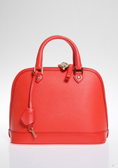 A leather designer handbag, against a white background, shot in a studio with sharp light and vivid blue and pink colours