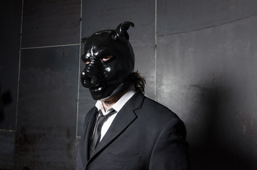 A corporate man in a dirty scruffy suit wearing a black pigs mask in a dark sinister background,...