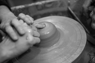 Hands working on a spinning pottery wheel, making pottery out of clay mud. close up photograph with a shallow depth of field.