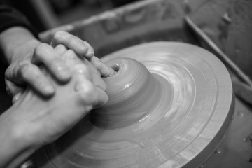 Hands working on a spinning pottery wheel, making pottery out of clay mud. close up photograph with a shallow depth of field.