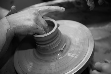 Hands working on a spinning pottery wheel, making pottery out of clay mud. close up photograph with a shallow depth of field.