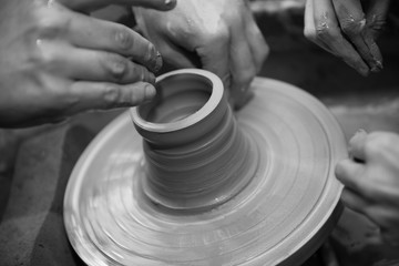 Hands working on a spinning pottery wheel, making pottery out of clay mud. close up photograph with a shallow depth of field.