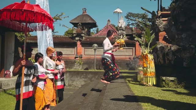 Balinese procession in temple with offerings, umbrella and white flag