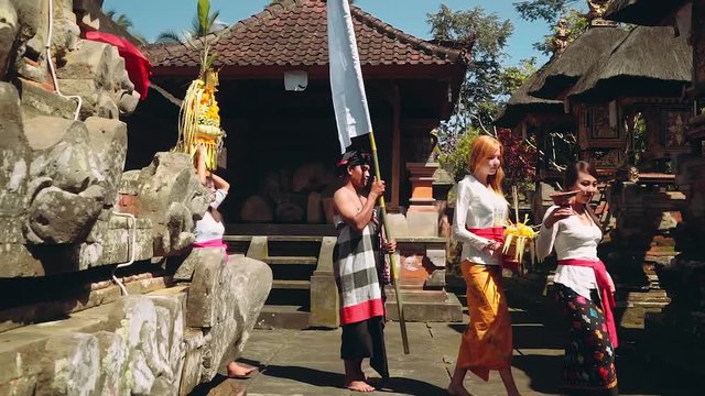 Balinese procession going to temple with offerings, umbrella and white flag
