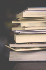 close up on book stacks with dark blurred background on vintage tone