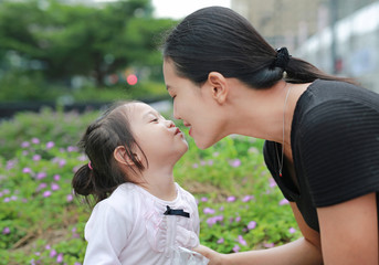 Mother and child girl kissing on bubble gum. Happy loving family.