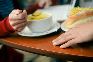 Closeup of female eating and working on laptop computer, wooden table background. Modern meeting busy communication lifestyle concept