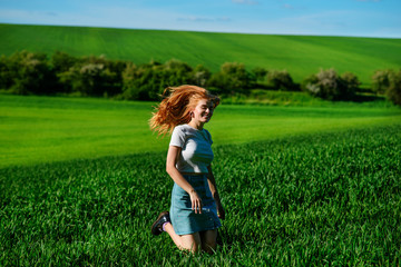 Fototapeta premium Young beautiful woman running on a green field