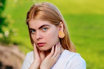 Fototapeta premium Portrait of a young beautiful woman with wooden tunnels in her ears