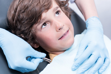 dentist preparing little boy for examining teeth in dentist office