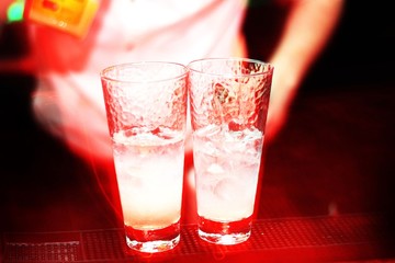 Two glasses of ice and vodka. Cocktail preparation. Night bar, party and barman. Cocktails in a red light spot