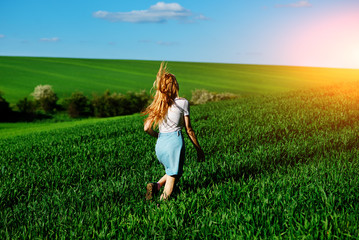Fototapeta premium Young beautiful woman running on a green field
