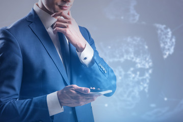 Pensive young man is using modern mobile phone