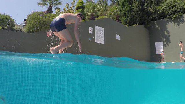 boy diving into a swimming pool, half underwater close up, raw, 4k