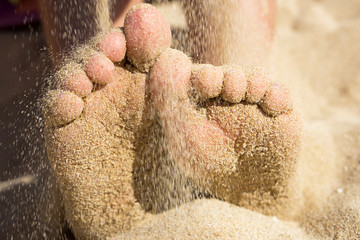 Child feet covered with sand on the beach