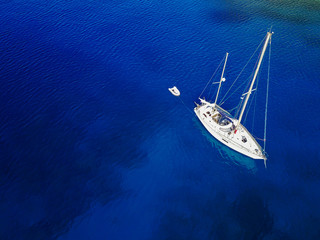Aerial shot of beautiful blue lagoon at hot summer day. Top view of sailing boat ready for cruise.