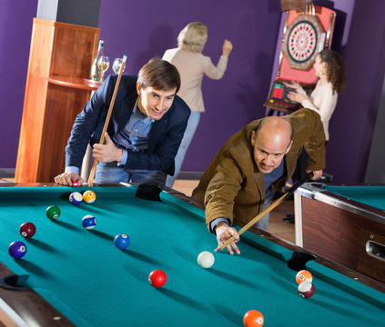 Group of happy charming positive friends playing billiards