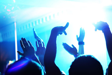 Silhouettes of many hands in a nightclub on the dance floor. Blue club light. dancing people. Atmosphere of fun