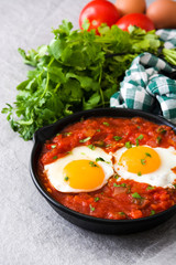 Mexican breakfast: Huevos rancheros in iron frying pan on gray stone