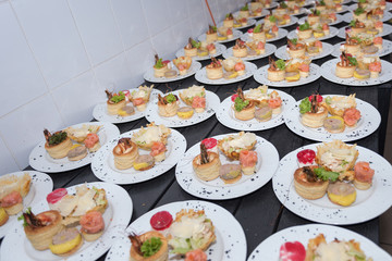 Many plates of appetizers being prepared in commercial kitchen, for an event