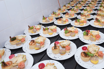 Many plates of appetizers being prepared in commercial kitchen, for an event