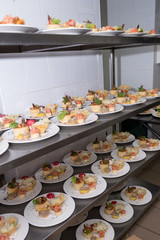 Many plates of appetizers being prepared in commercial kitchen, for an event