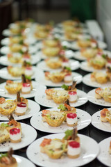 Many plates of appetizers being prepared in commercial kitchen, for an event