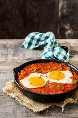 Mexican breakfast: Huevos rancheros in iron frying pan on wooden table