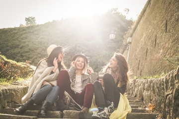 Obraz premium Three young girls sitting on the stairs at the public park. Three young girls sitting on the stairs at the public park an having conversation.