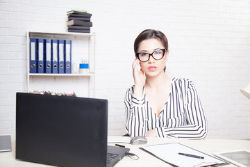 business girl sits at a computer in the Office paper folders