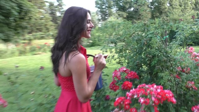 Young woman takes care of the flowers in her garden.