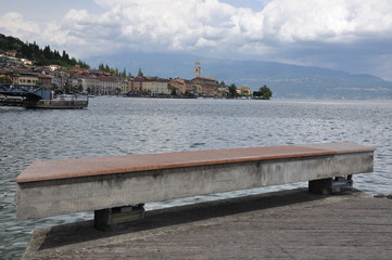 Single bench on shore of calm lake and mountains