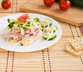 Breakfast. Salad with fried eggs, ham, cucumber, onion, tomatoes