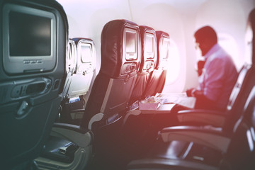 Naklejka premium Blurry image of airplane interior with incidental passenger sitting on seats - travel concept, retro styled.