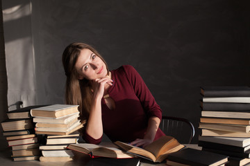 the girl sitting at the table reading a lot of books