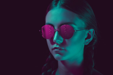headshot of thoughtful young woman in stylish round sunglasses