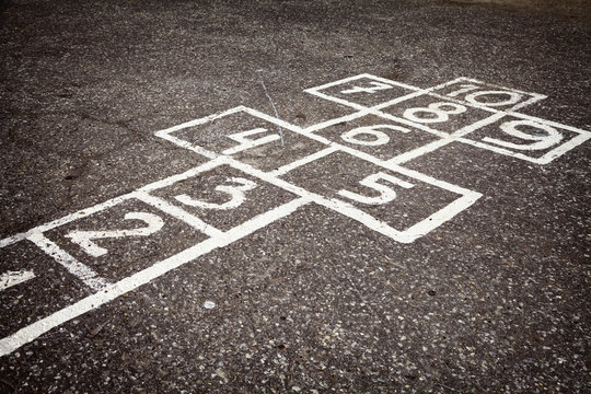 Hopscotch court with numbers from 1 to 10 drawn with white paint on the asphalt