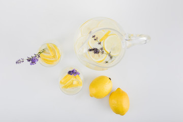 top view of fresh citrus drinks with lavender flowers in glasses and jar isolated on white