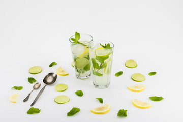 refreshing citrus beverages in glasses and spoons isolated on white