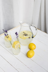 high angle view of citrus drinks with lavender in glasses and jar on wooden table